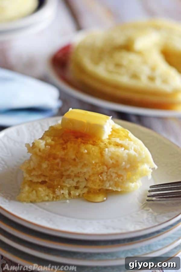 Moroccan Baghrir Thousand Hole Semolina Pancakes 3 A serving of Moroccan Baghrir pancakes cut into quarters and arranged on a white plate, generously drizzled with butter and honey.