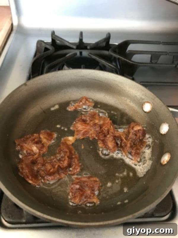A quarter cup of creamy date paste (Agwa) and a tablespoon of butter melting and softening together in a hot skillet, marking the initial step of the preparation process.