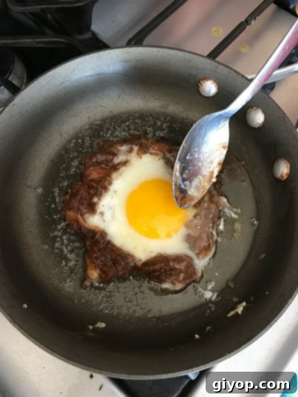 A close-up of the fully cooked Egg Agwa still in the pan, showcasing the egg perfectly set within the date paste ring and ready to be carefully removed and served, highlighting the delicious textures.