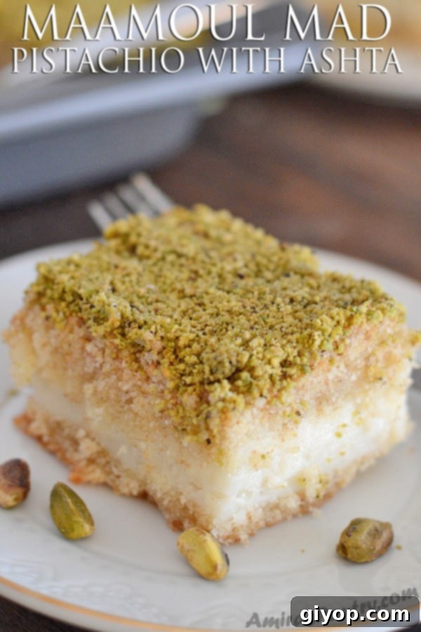 Pistachio-Packed Maamoul with Velvety Ashta 2 A close up of a slice of Ma'mool Mad with creamy Ashta filling, garnished with vibrant green pistachios, sitting on a white plate.
