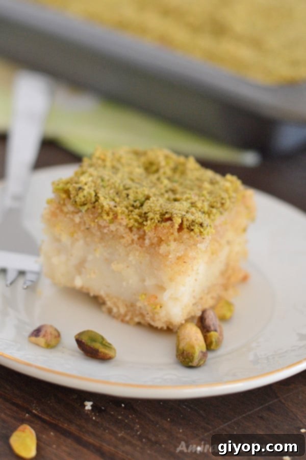 Pistachio-Packed Maamoul with Velvety Ashta 14 A beautifully sliced piece of Ma'mool Mad with Ashta, featuring its distinct layers and a generous topping of ground pistachios.