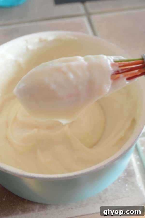 Pistachio-Packed Maamoul with Velvety Ashta 9 A pan on the stove, showing the Ashta mixture thickening and being stirred with a spoon, reaching its desired creamy consistency.