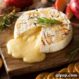 A brie wheel on a wooden surface oozing with cheese.