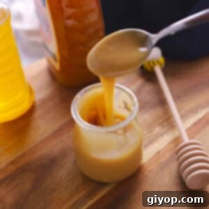Small metal spoon scooping some whipped honey off a jar.