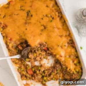 A zoomed in image of a casserole dish with a serving spoon, showcasing the delicious texture of the hamburger rice casserole.