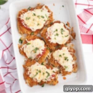 An overhead image of a white casserole dish with chicken parmesan thighs garnished with basil.