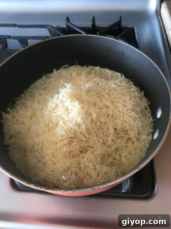 Tricolor Ice Cream Knafeh Delight 5 A pan of food on a stove, with knafeh pastry