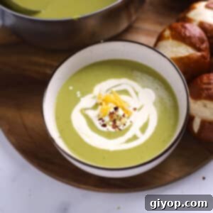 An overhead image of a bowl with asparagus soup on a wooden board.
