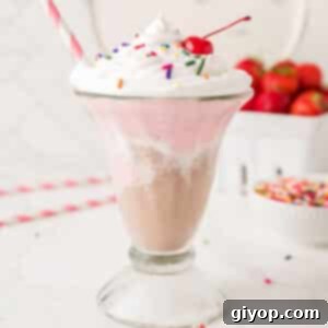 A tall glass cup with Neapolitan milkshake with a straw in the cup.