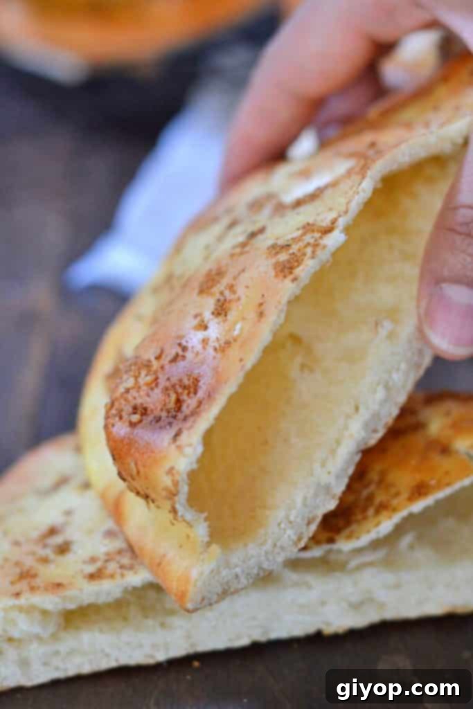 A hand presenting a perfectly baked Khameer bread pocket, ready for stuffing