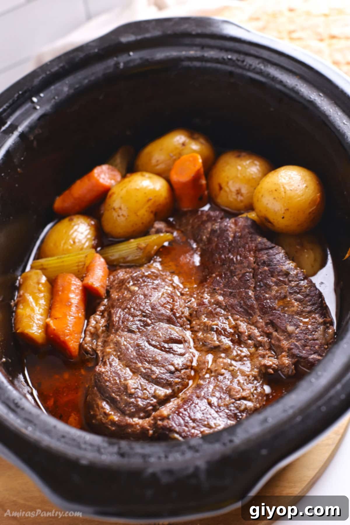 An overhead image of a slow cooker with pot roast and vegetables, ready to be served.