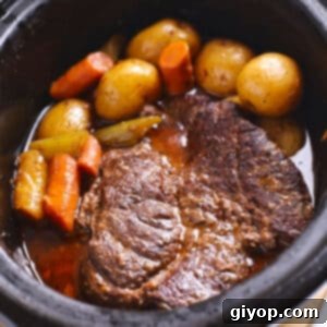 An overhead image of a black crockpot with pot roast and vegetables.