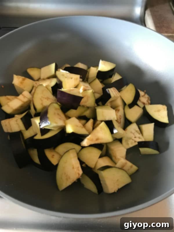 Vibrant Mediterranean Eggplant Salad 2 A pan filled with freshly diced eggplant pieces, ready to be cooked to a golden brown perfection. The eggplant cubes are evenly cut, ensuring consistent cooking.