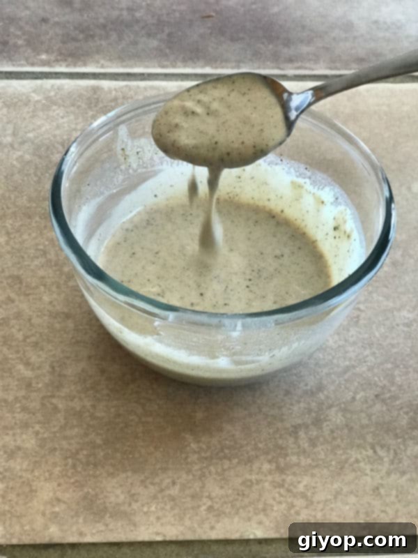 Vibrant Mediterranean Eggplant Salad 3 A clean, white bowl containing the creamy and luscious tahini-yogurt dressing, perfectly whisked and ready to be drizzled over the eggplant salad.