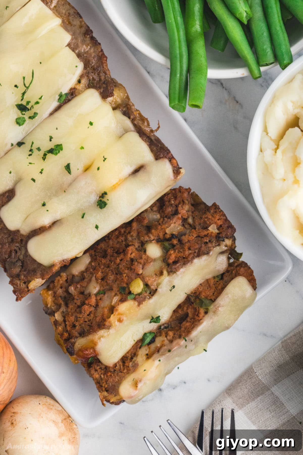 A perfectly baked Philly Cheesesteak Meatloaf, sliced and ready to serve, showing the melted cheese and colorful vegetables inside.