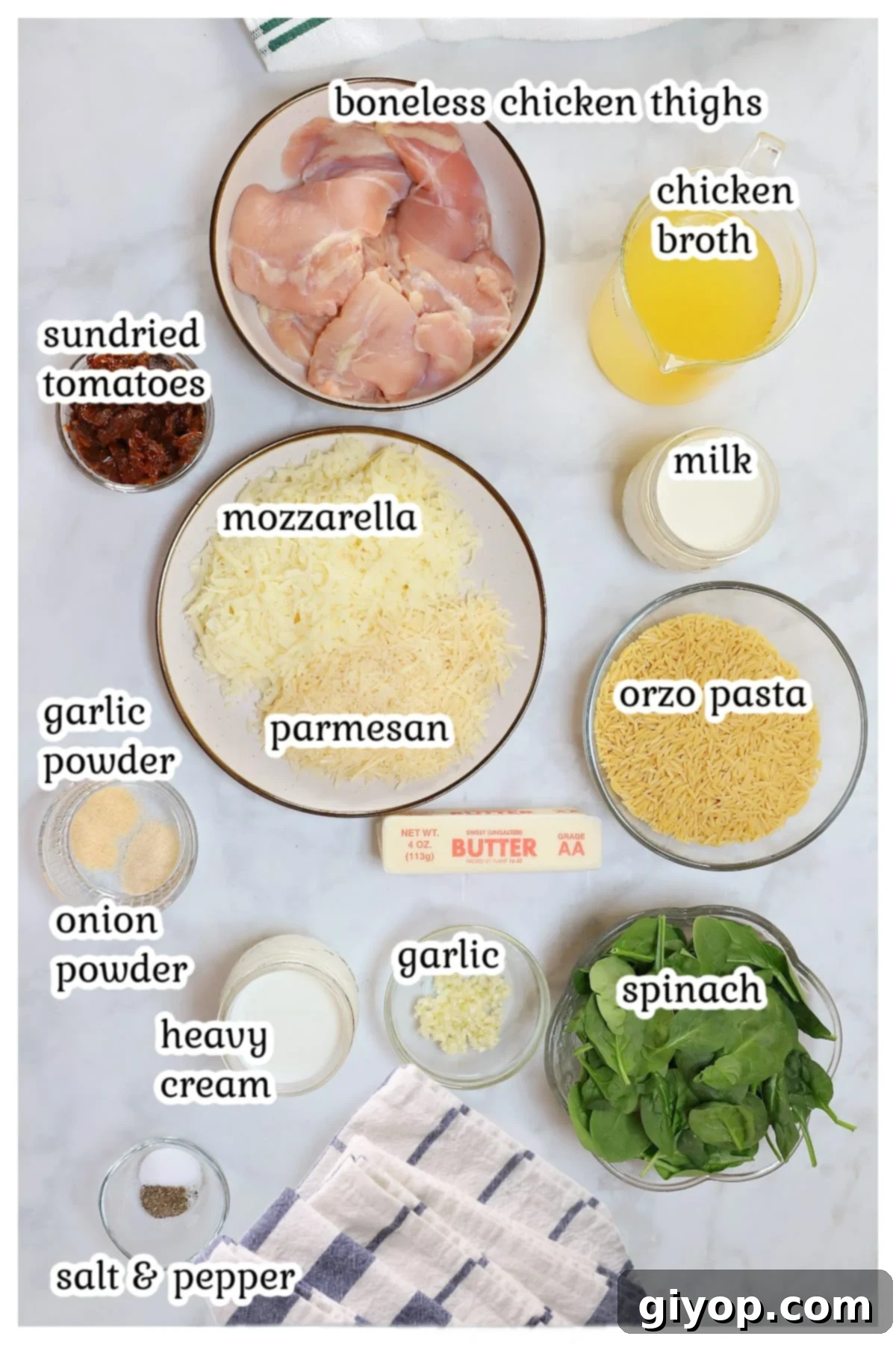 A vibrant flat lay of all the fresh ingredients for Tuscan Chicken Orzo, including chicken, orzo, sun-dried tomatoes, spinach, and various cheeses.