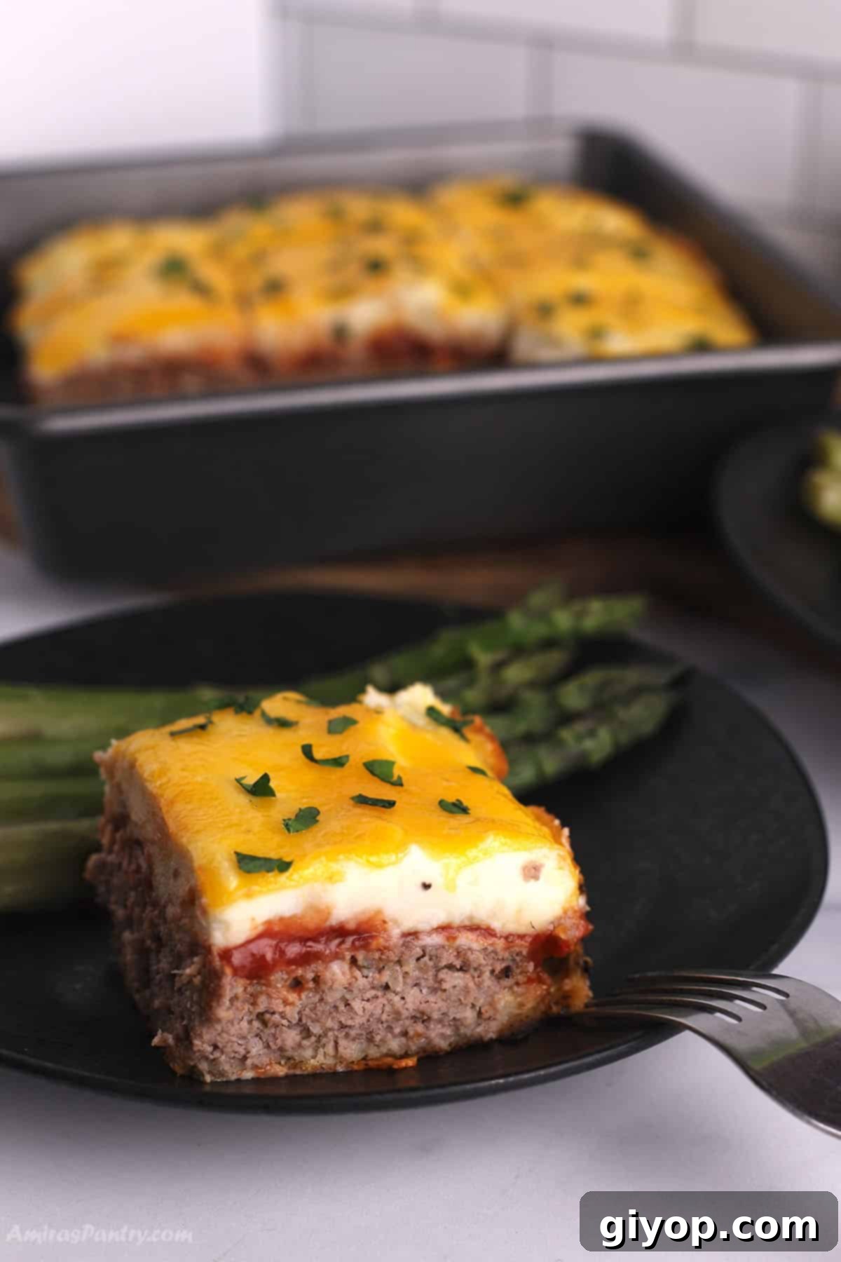 A generous slice of Meatloaf Casserole served on a black plate, showcasing its golden mashed potato topping and rich meat base.