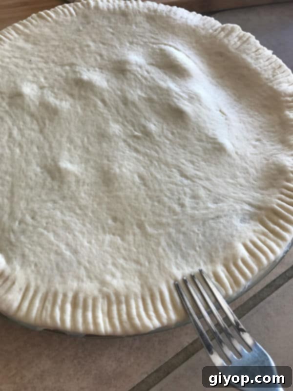 Placing the top crust over the shawarma filling.