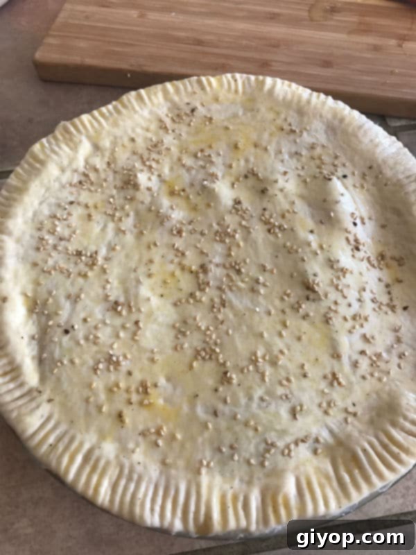 Egg wash and sesame seeds applied to the shawarma pie before baking.