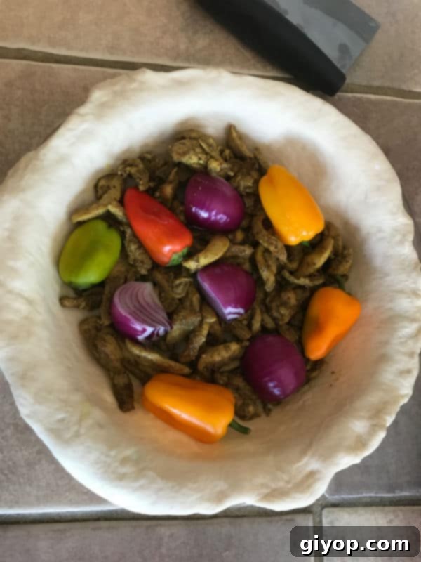 Shawarma filling and vegetables on the bottom pie crust.