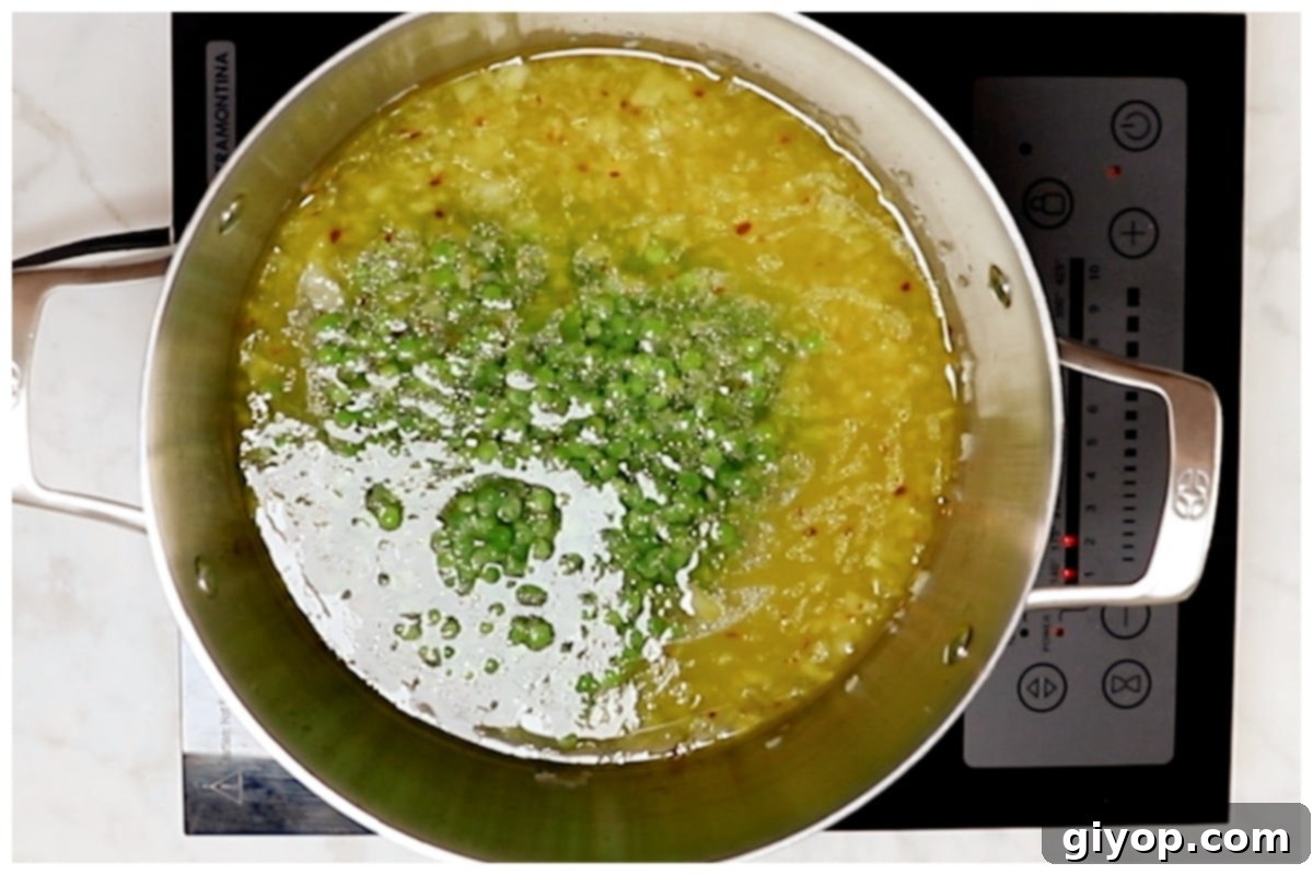 Creamy Pasta with Peas 5 Frozen peas boiling with sautéed onions and water in a large pot, ready to incorporate the pasta.