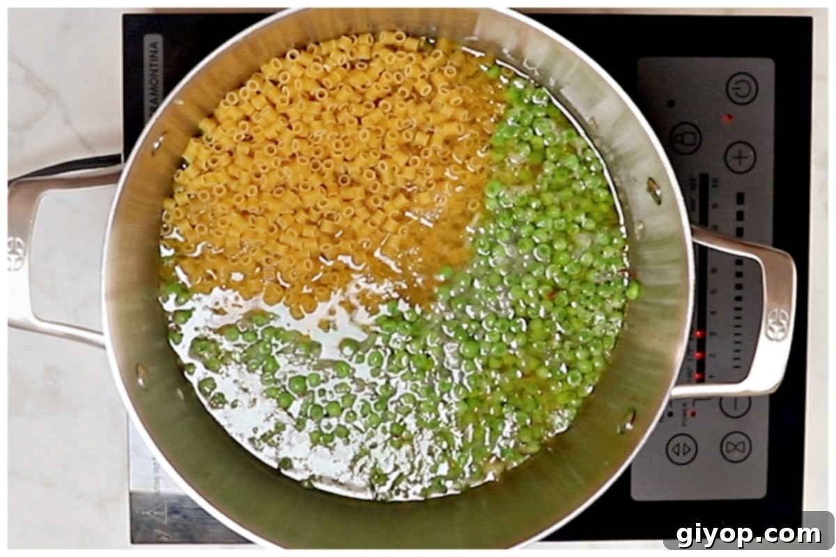 Creamy Pasta with Peas 7 Ditalini pasta cooking in a large pot with peas and a flavorful broth, stirred frequently to create a creamy sauce.