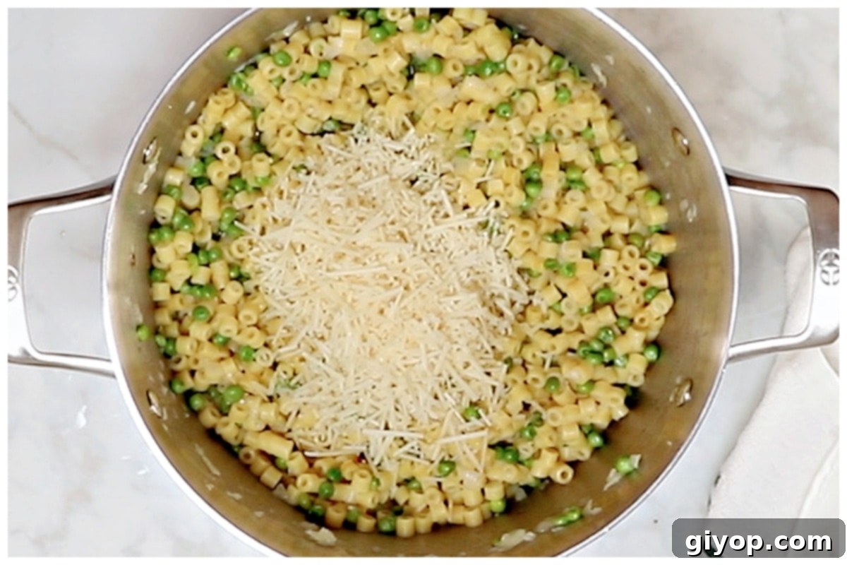 Creamy Pasta with Peas 8 A large pot of freshly prepared Pasta e Piselli, generously topped with grated Parmesan cheese, ready to be served.