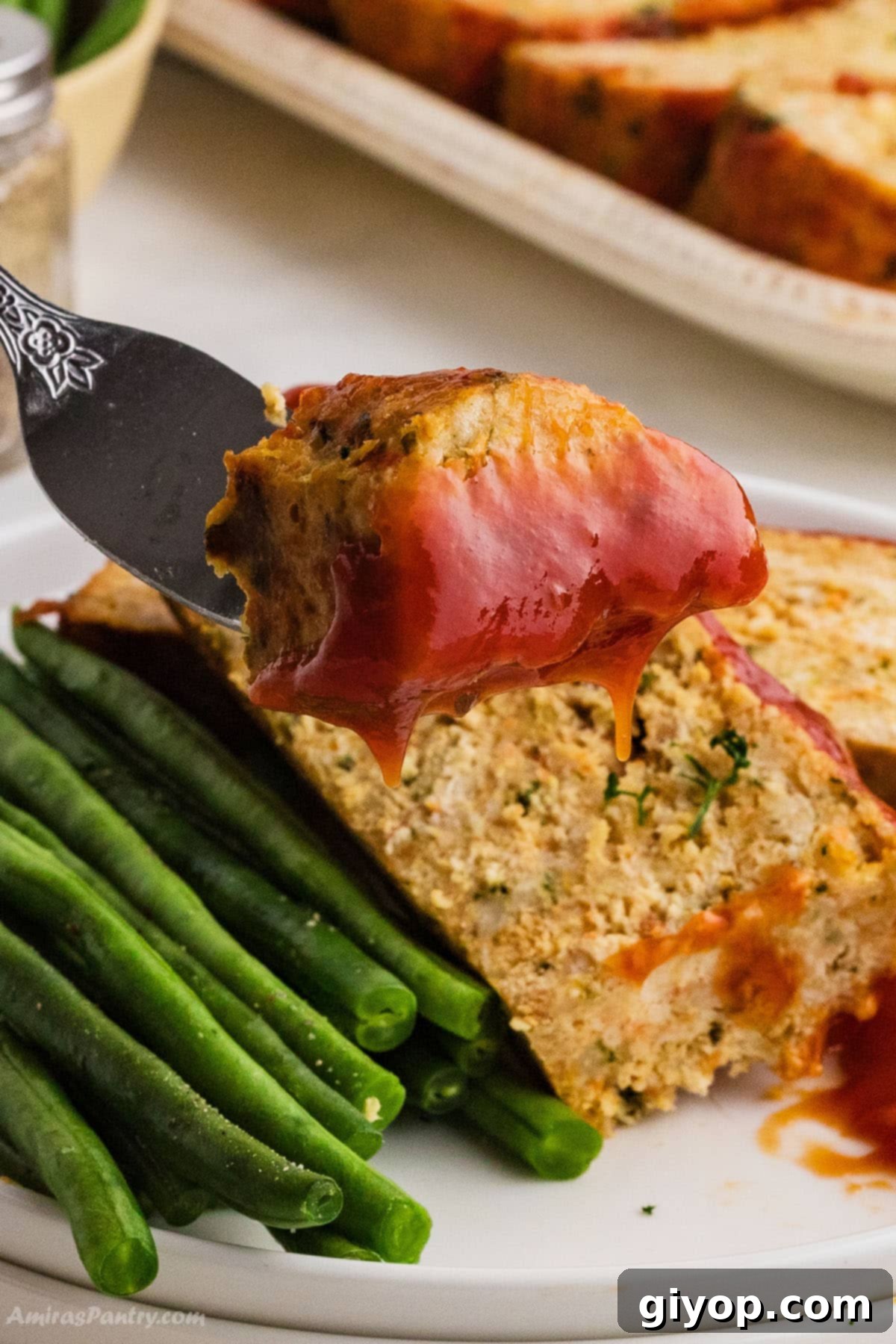 Hearty Chicken Meatloaf 5 A fork with a piece of chicken meatloaf with sauce, showing its moist texture.