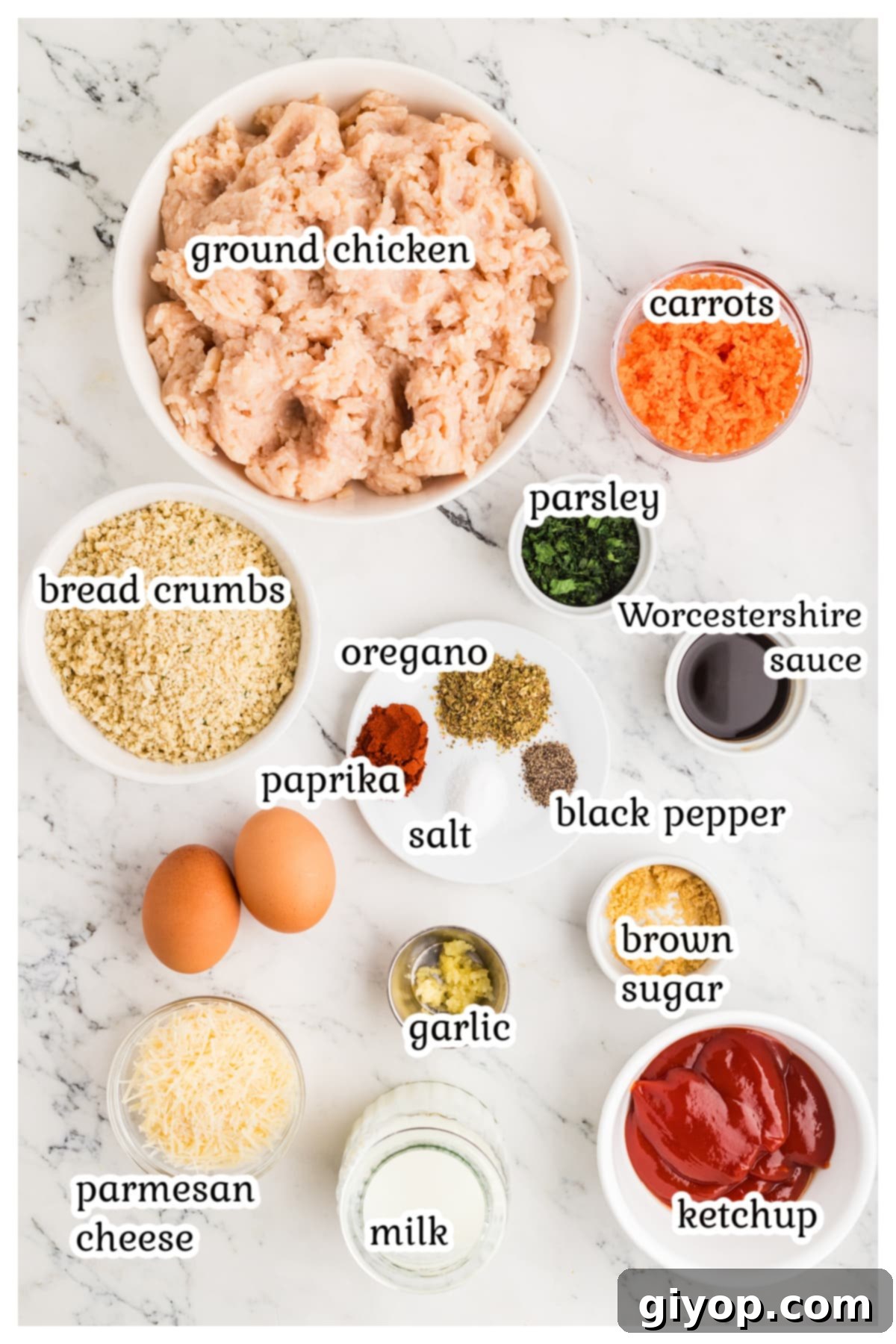 Hearty Chicken Meatloaf 3 Fresh ingredients laid out for chicken meatloaf preparation: ground chicken, carrots, cheese, bread crumbs, eggs, and herbs.