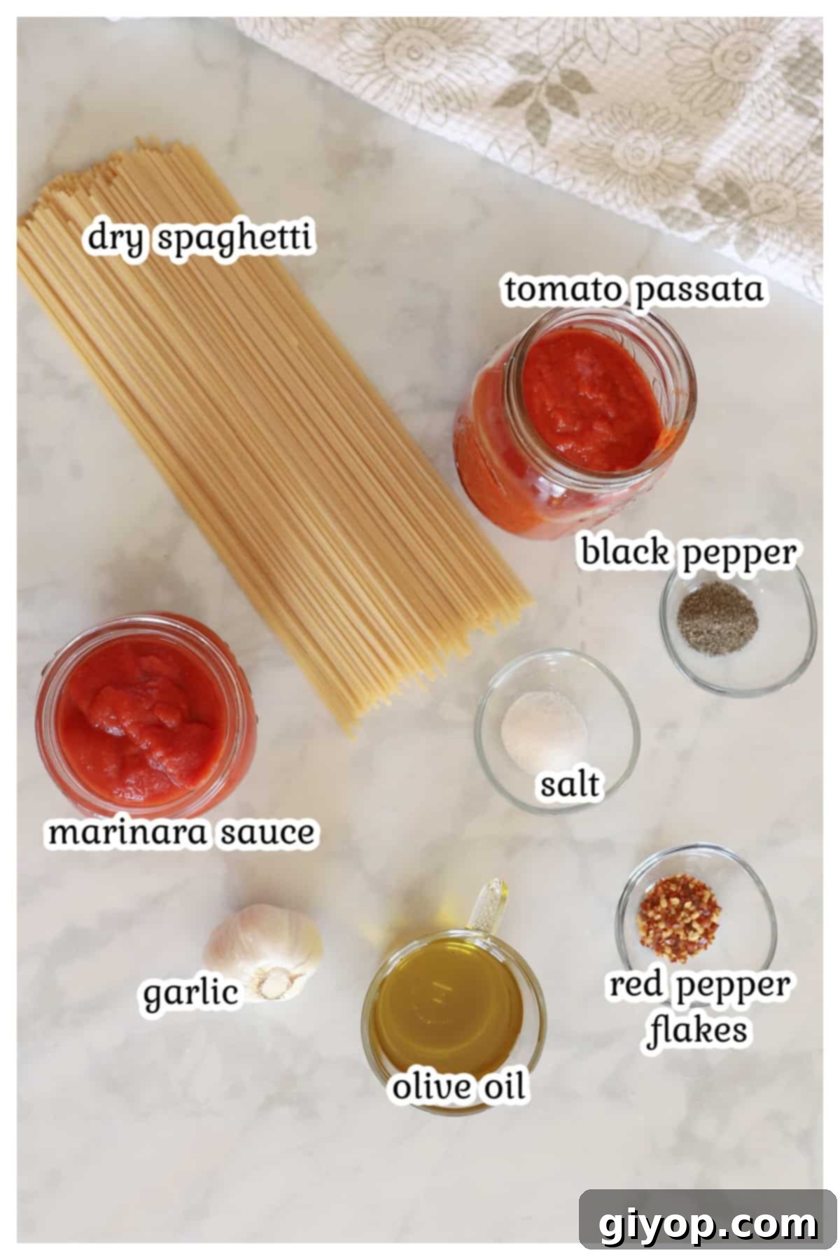 A flat lay of ingredients for Spaghetti all'Assassina, including spaghetti, tomato passata, marinara sauce, garlic, olive oil, and red pepper flakes.