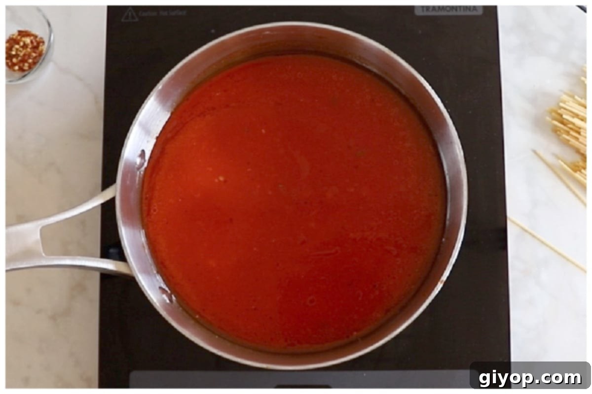 A saucepan filled with a vibrant red tomato sauce simmering gently.