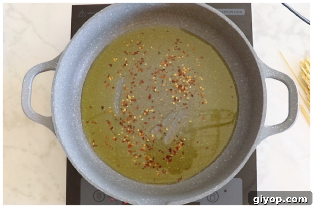 Red chili pepper flakes sizzling in hot olive oil in a wide skillet.