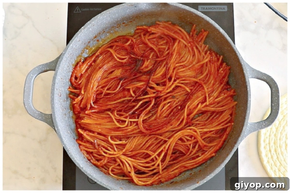 Close-up of scorched and caramelized spaghetti strands at the bottom of a skillet.