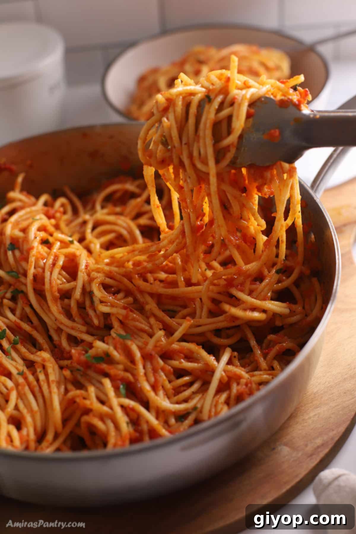 Harissa pasta served with kitchen tongs, ready to be enjoyed as a quick and flavorful meal.