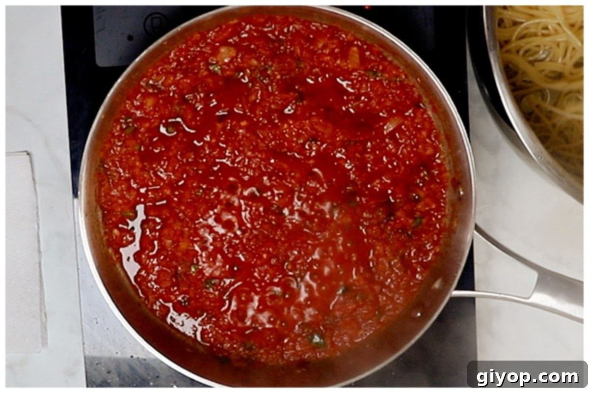 The rich tomato harissa sauce bubbling gently in a skillet, its flavors intensifying as it simmers.