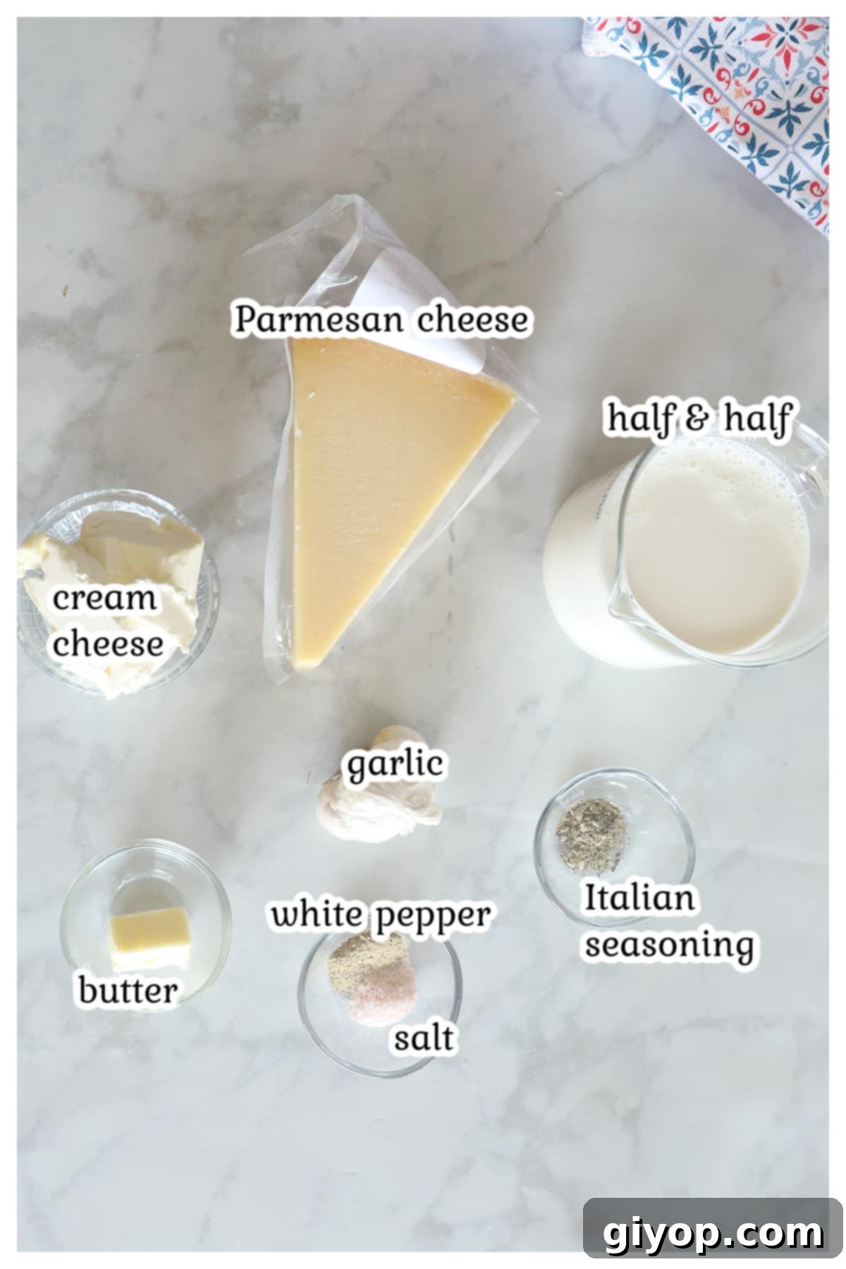 Fresh ingredients laid out for homemade Alfredo sauce with half and half, including butter, garlic, cream cheese, half-and-half, Parmesan, and seasonings.