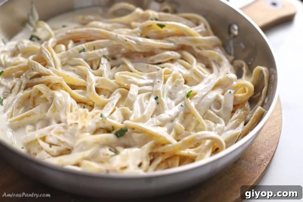 A skillet filled with creamy Alfredo fettuccine pasta, beautifully garnished with fresh green parsley, ready to be served.