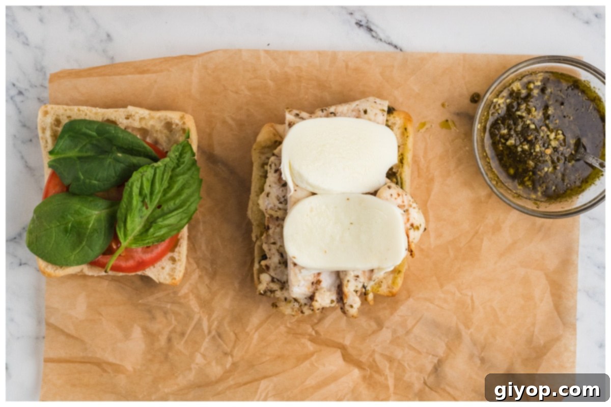 Sun-Kissed Caprese Chicken Sandwich 10 An assembled Chicken Caprese sandwich, cut in half, showcasing layers of chicken, mozzarella, tomato, and basil.