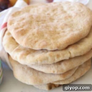 A stack of golden brown Taboon bread with a white towel in the background, signaling freshness and warmth.