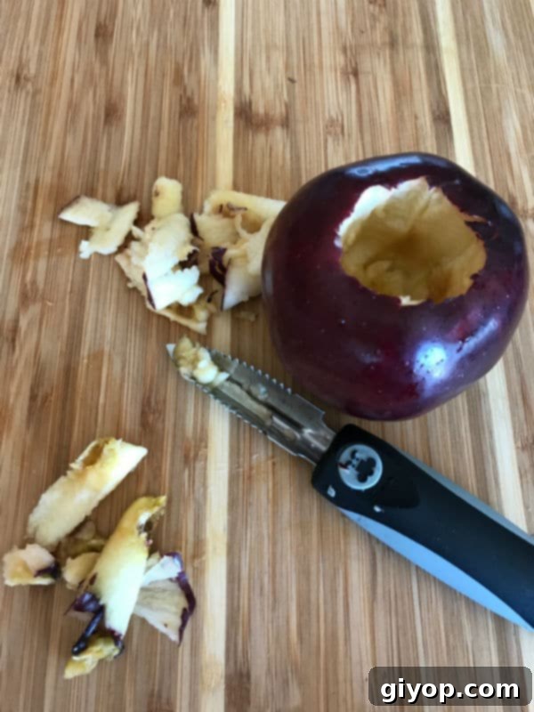 A freshly cored red apple sitting on a wooden cutting board, ready for stuffing.