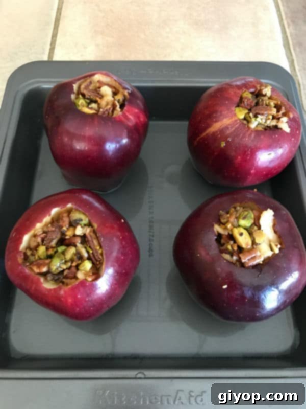 A baking pan filled with red apples, generously stuffed with the baklava nut mixture, ready for the oven.
