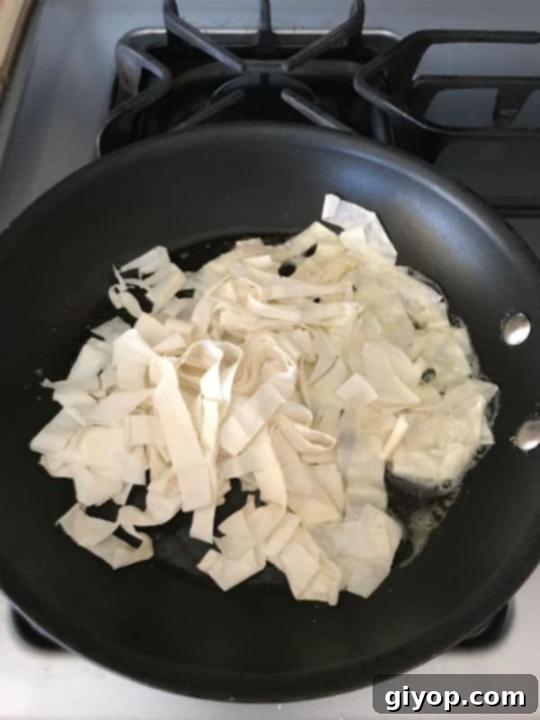 A pan with shredded phyllo dough being toasted in butter until golden brown.