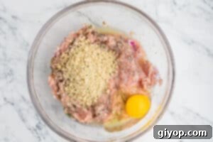 A glass bowl with panko breadcrumbs and eggs added to the ground chicken mix.