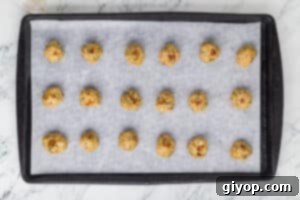 Baked chicken meatballs arranged on a baking sheet lined with parchment paper, fresh out of the oven.