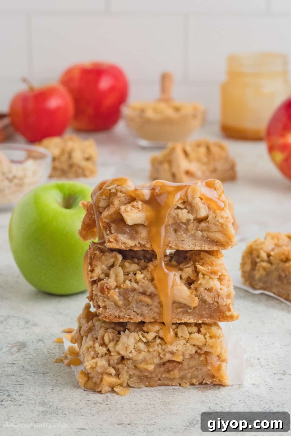Decadent Salted Caramel Apple Pie Bars 2 A stack of golden-brown apple pie bars generously drizzled with rich, homemade salted caramel sauce, inviting you to take a bite. Fresh apples and cinnamon sticks are scattered in the background, hinting at the delightful fall flavors within.