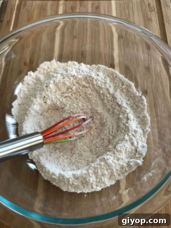 Dry ingredients for the chicken marinade in a clear glass bowl on a rustic wooden table.