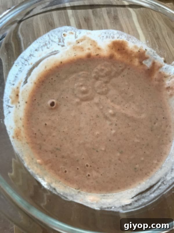 Marinade mixture being thoroughly stirred in a glass bowl to a smooth, liquid consistency.
