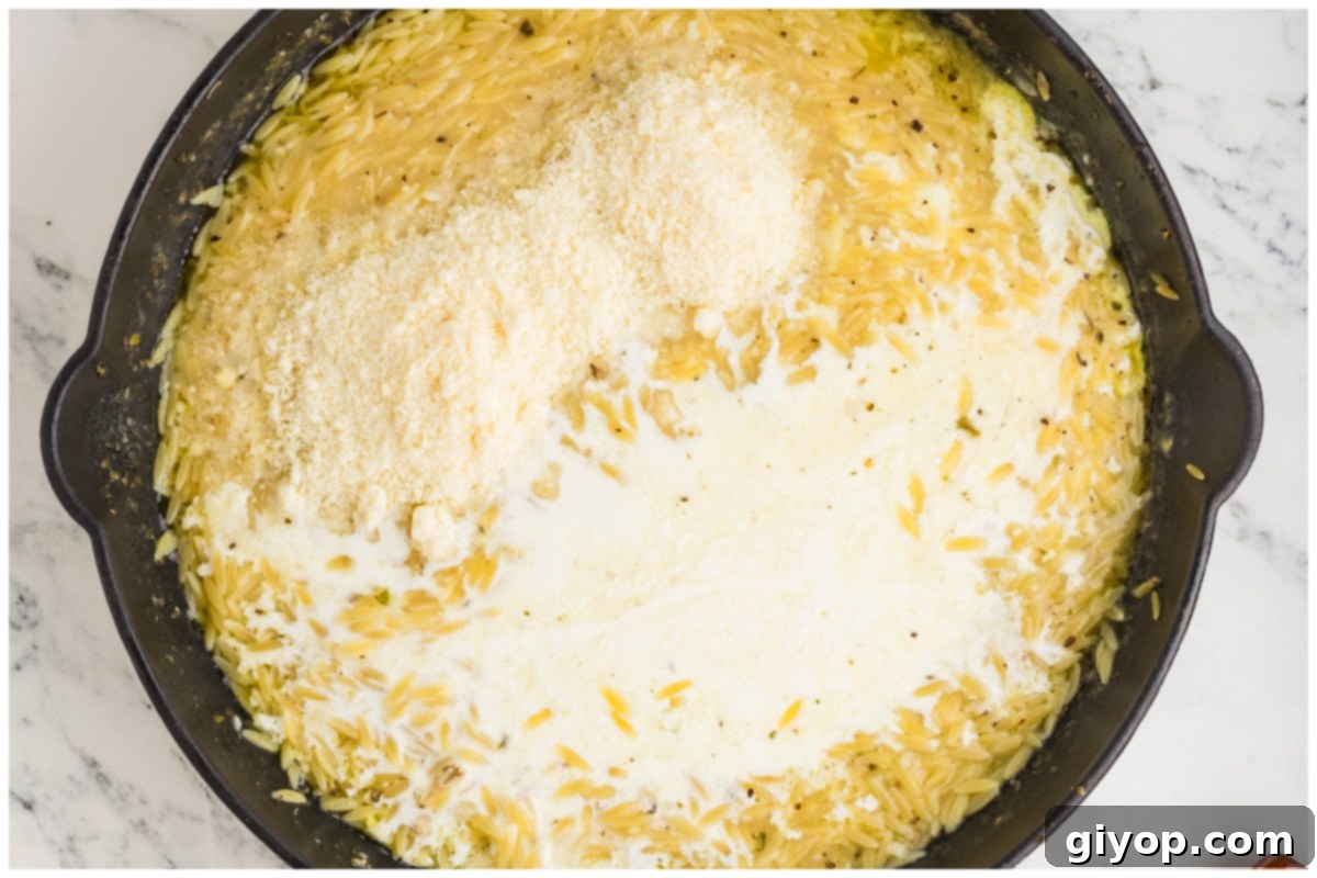 Bright Lemon Chicken Orzo 10 A large pot of creamy orzo pasta cooking with heavy cream and grated Parmesan cheese, forming a rich sauce.