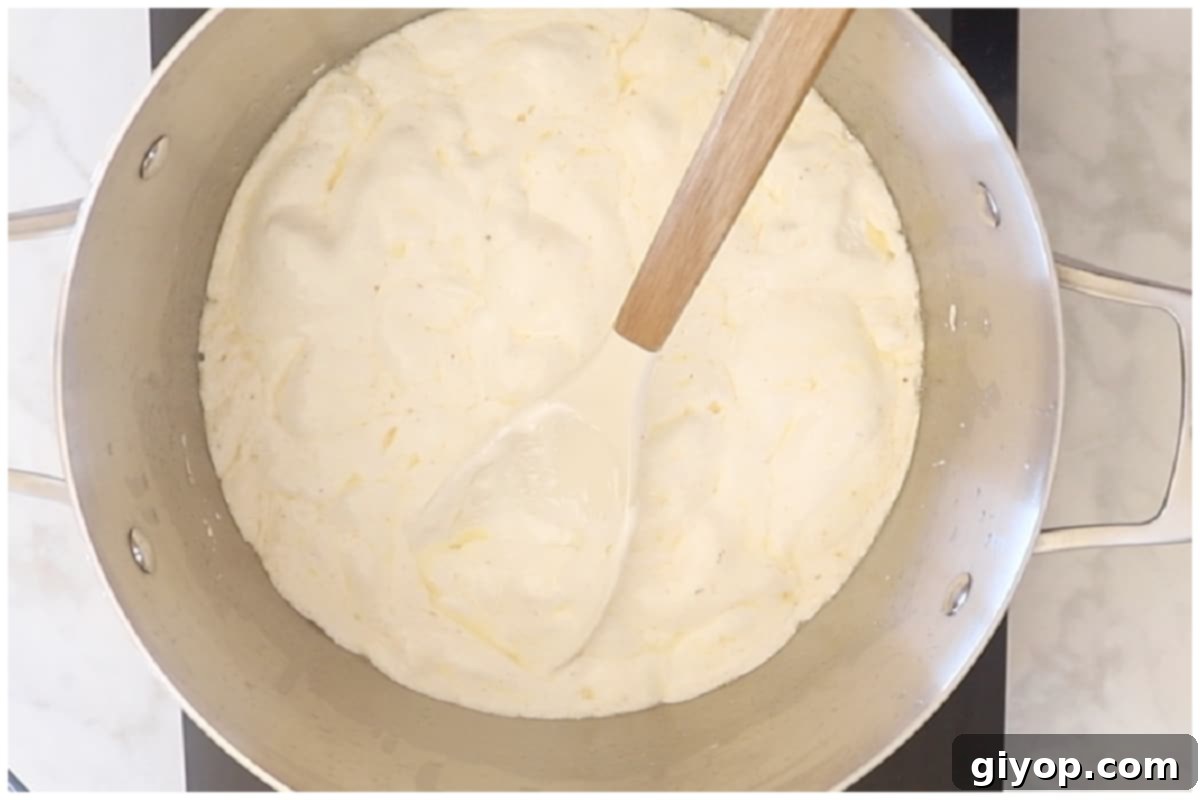 A large pot on low heat, containing melted butter and creamy marshmallow fluff being stirred into a smooth, luscious, and warm mixture.