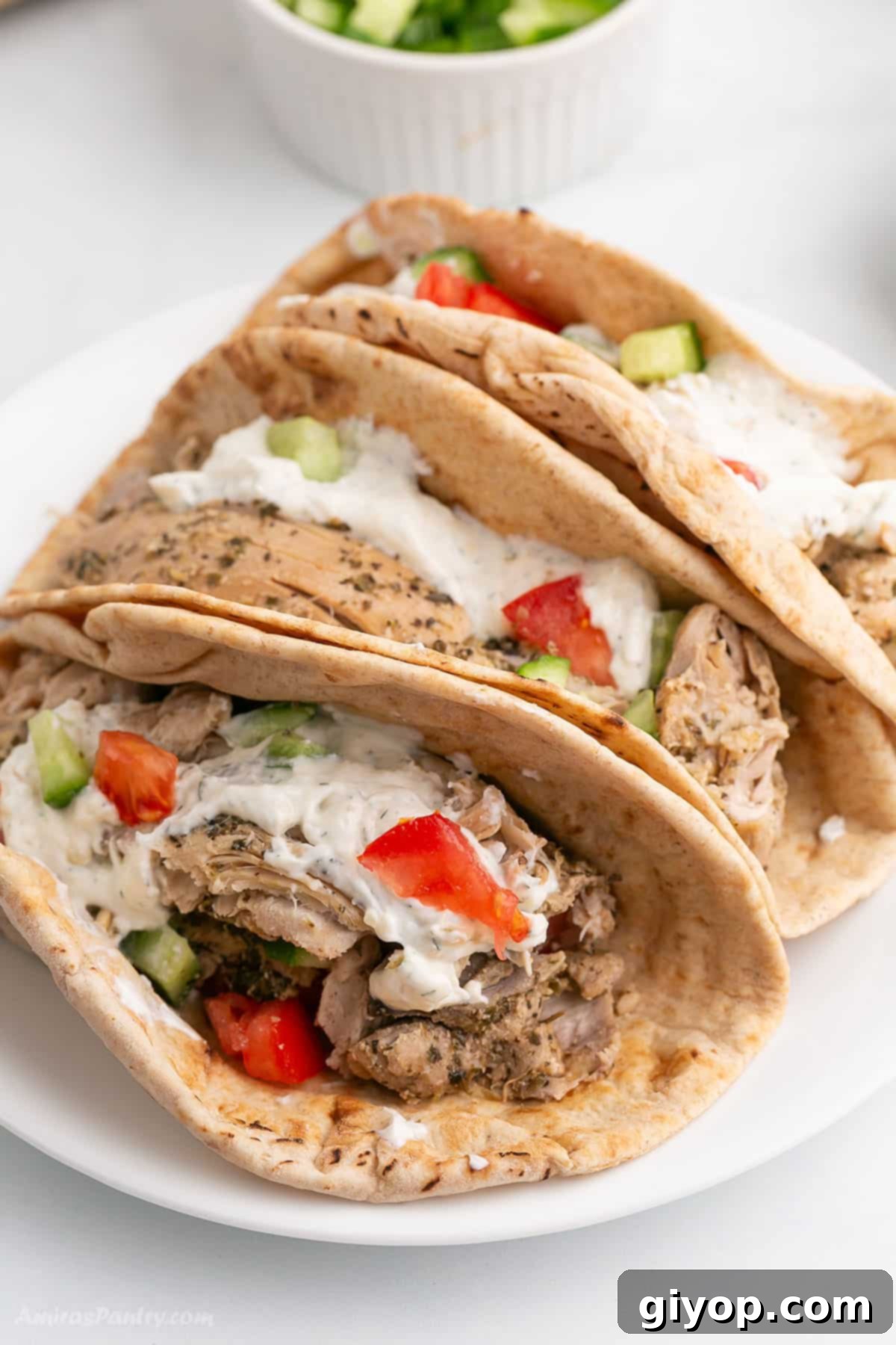 Set-It-and-Forget-It Chicken Gyros 2 Platter of freshly assembled Slow Cooker Chicken Gyros on warm pita bread with vibrant toppings.